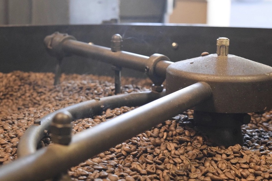 Freshly roasted coffee beans turning in the cooling tray of a drum roaster
