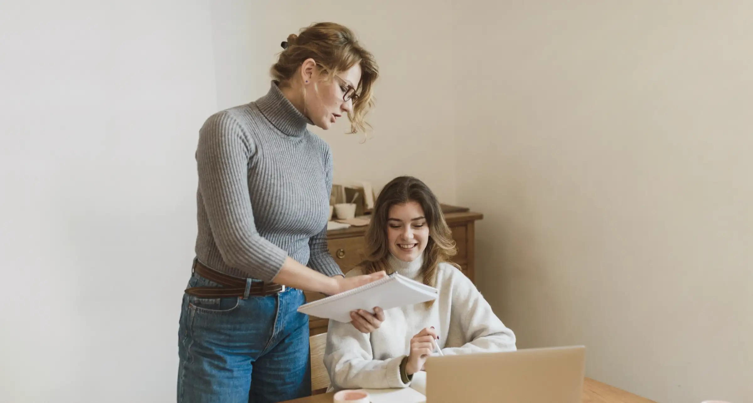 A preparer leaning over a client's papers at her desk while the client marks them up