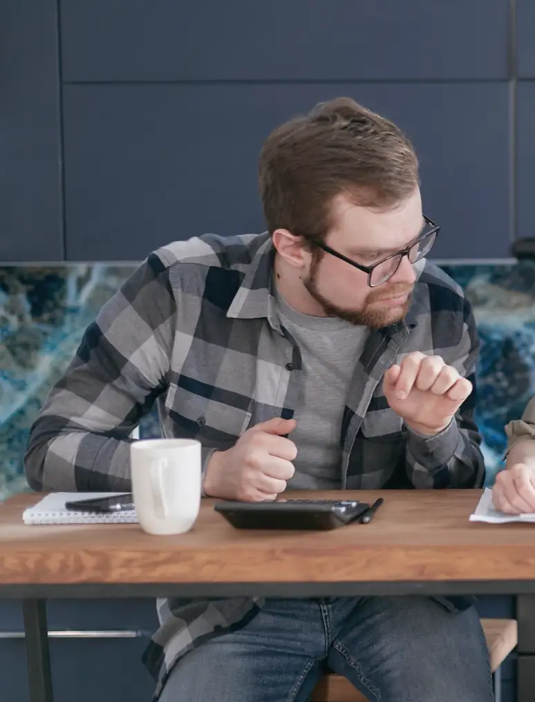 A contractor with a coffee and a calculator at his desk