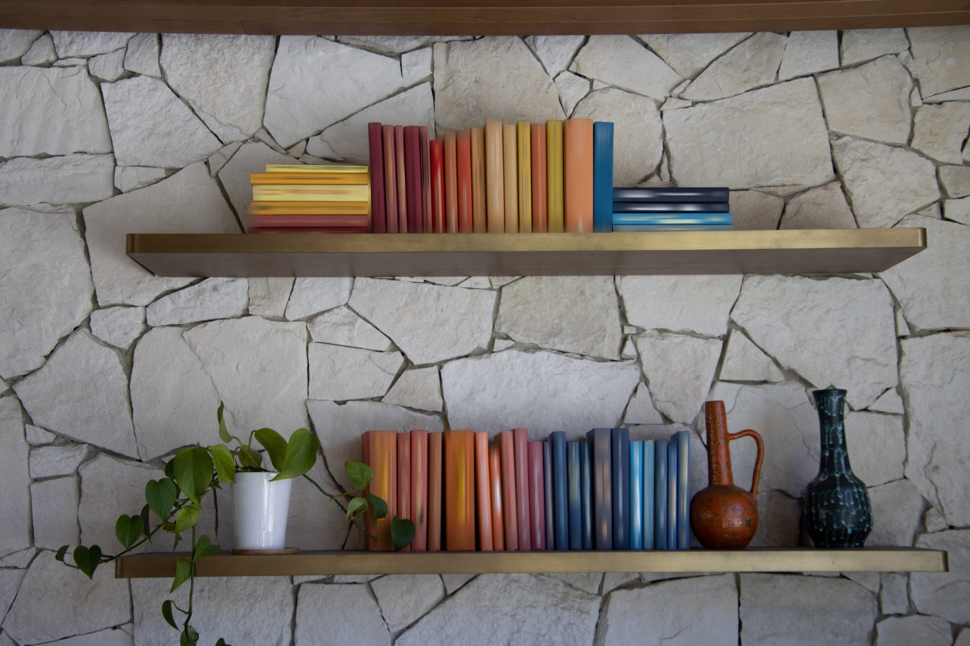 Two brass floating shelves on a whitewashed stone wall, holding books arranged by color, a trailing pothos, a terracotta jug and a dark glazed vase
