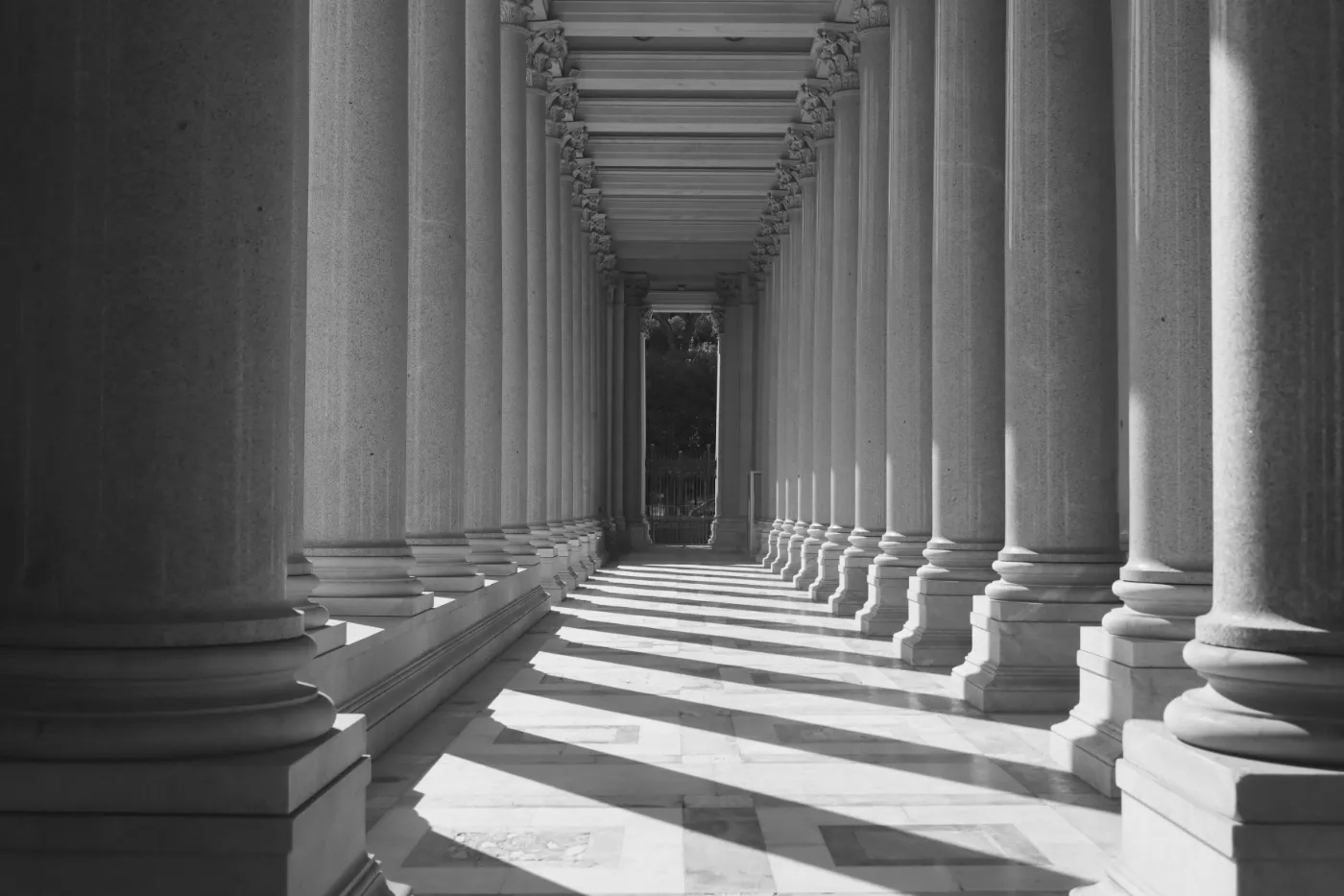 Sunlight falling between the stone columns of a colonnade