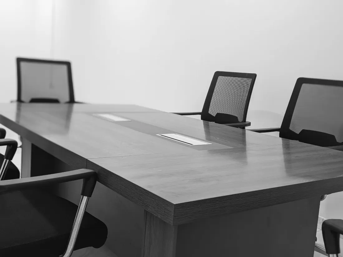 An empty conference table with black mesh chairs