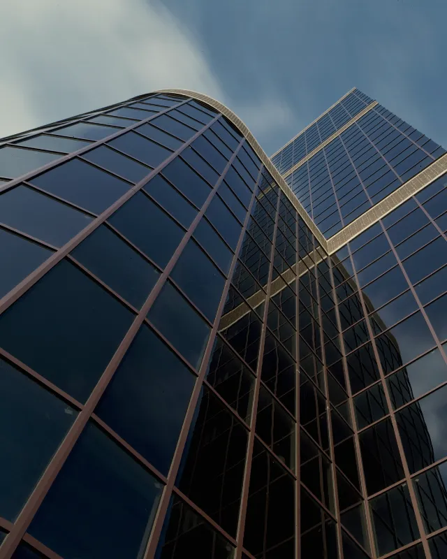 Looking up the angled glass grid of a modern office building.
