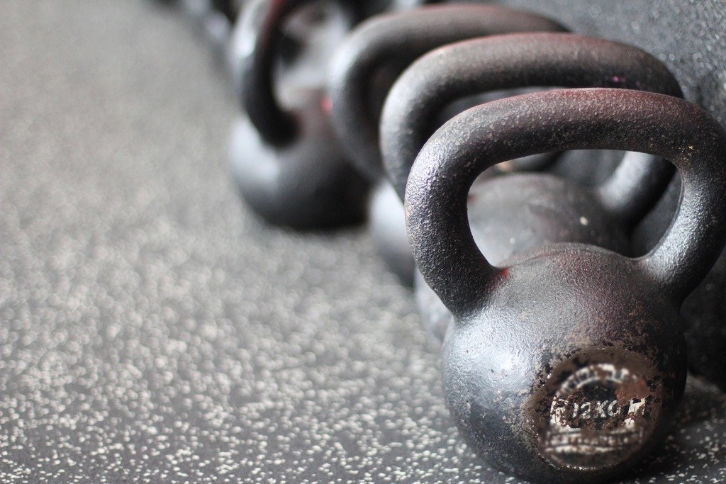 A row of cast-iron kettlebells on rubber gym flooring