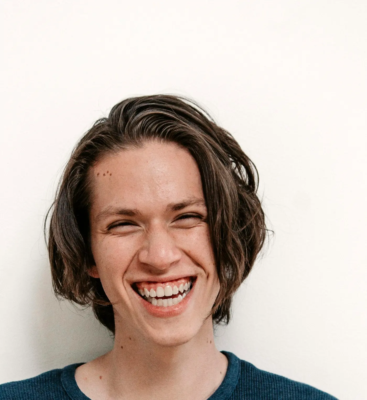 A young man laughing, showing straight white teeth