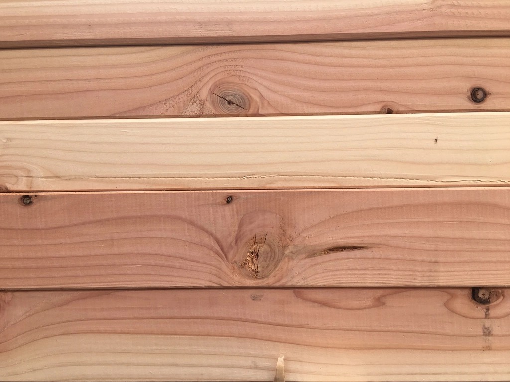 A stack of fir boards seen edge-on: pink and honey-colored grain, a few dark knots and a split along one board