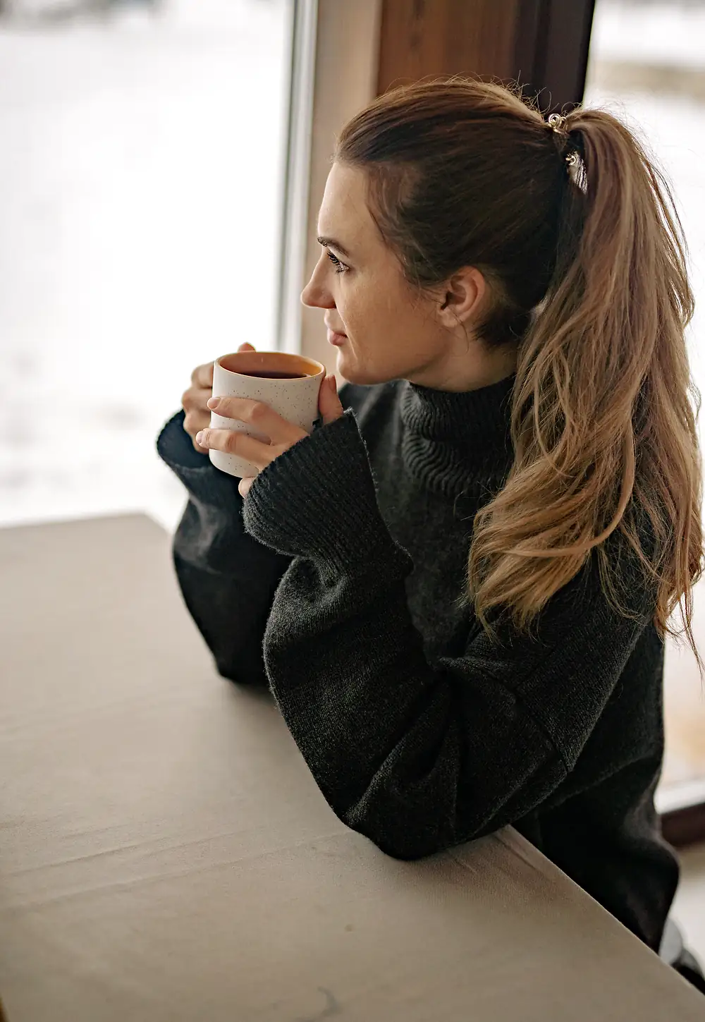 Grace, the homeowner, holds a mug of coffee and looks out her kitchen window.