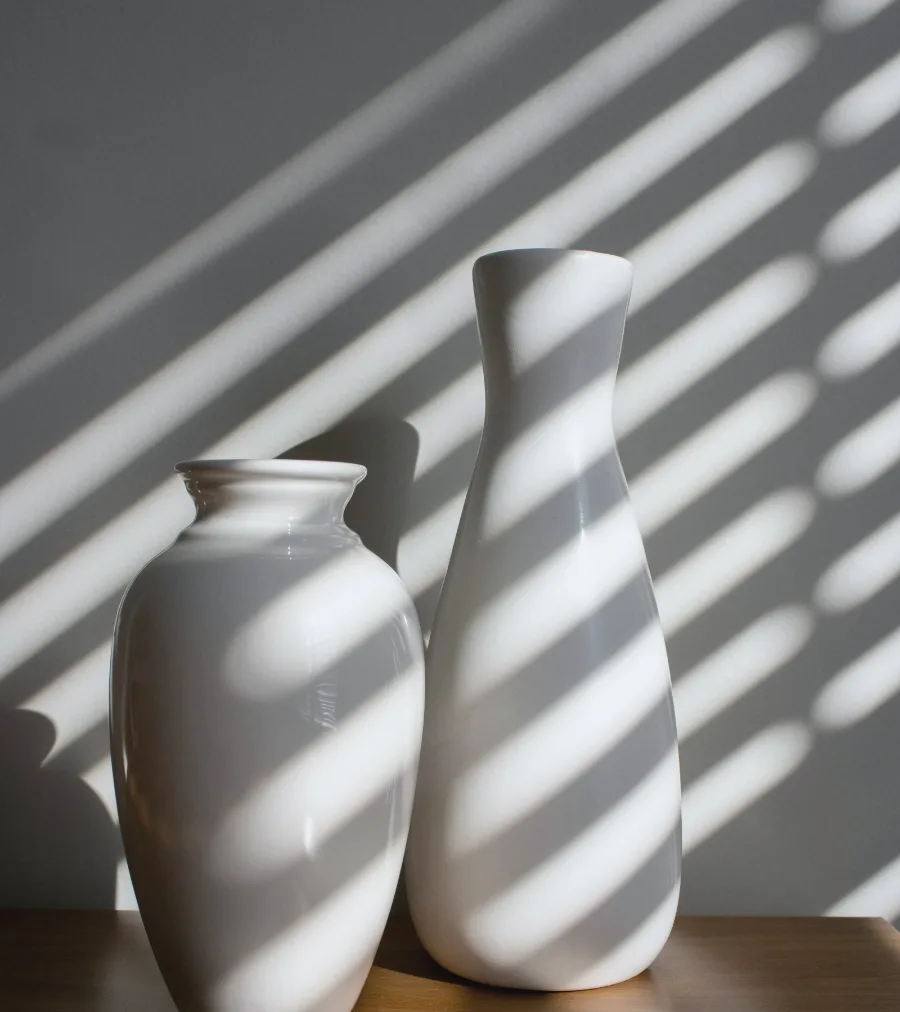 Two white ceramic vases striped with window light