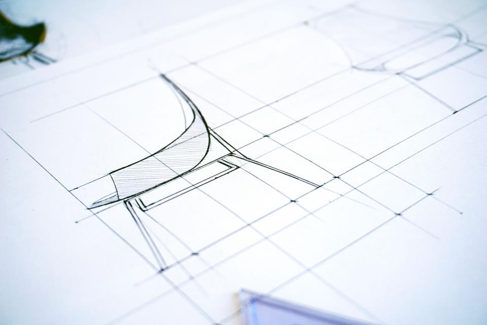 Pencil perspective sketch of a curved bench on drafting paper, with construction lines and a plastic set square