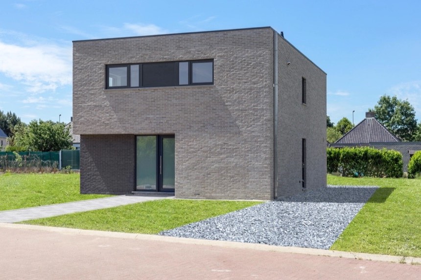 Two-storey house shaped as a plain cube of grey brick, with one long window strip and a tall glass door