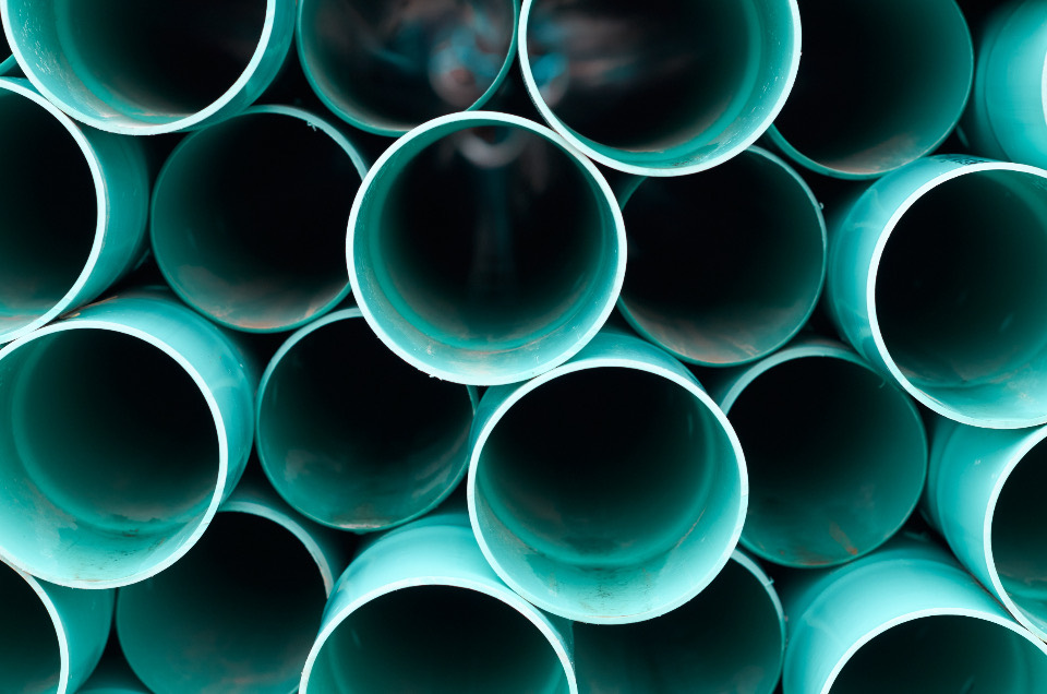 A stack of new PVC drain pipes, seen end-on