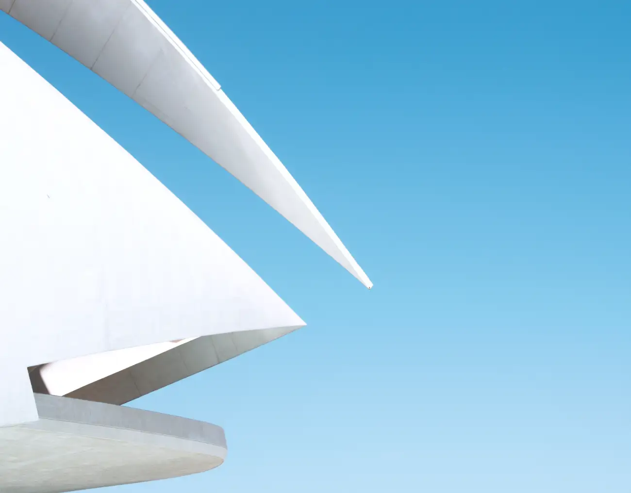 Sharp white architectural curves against a clear blue sky